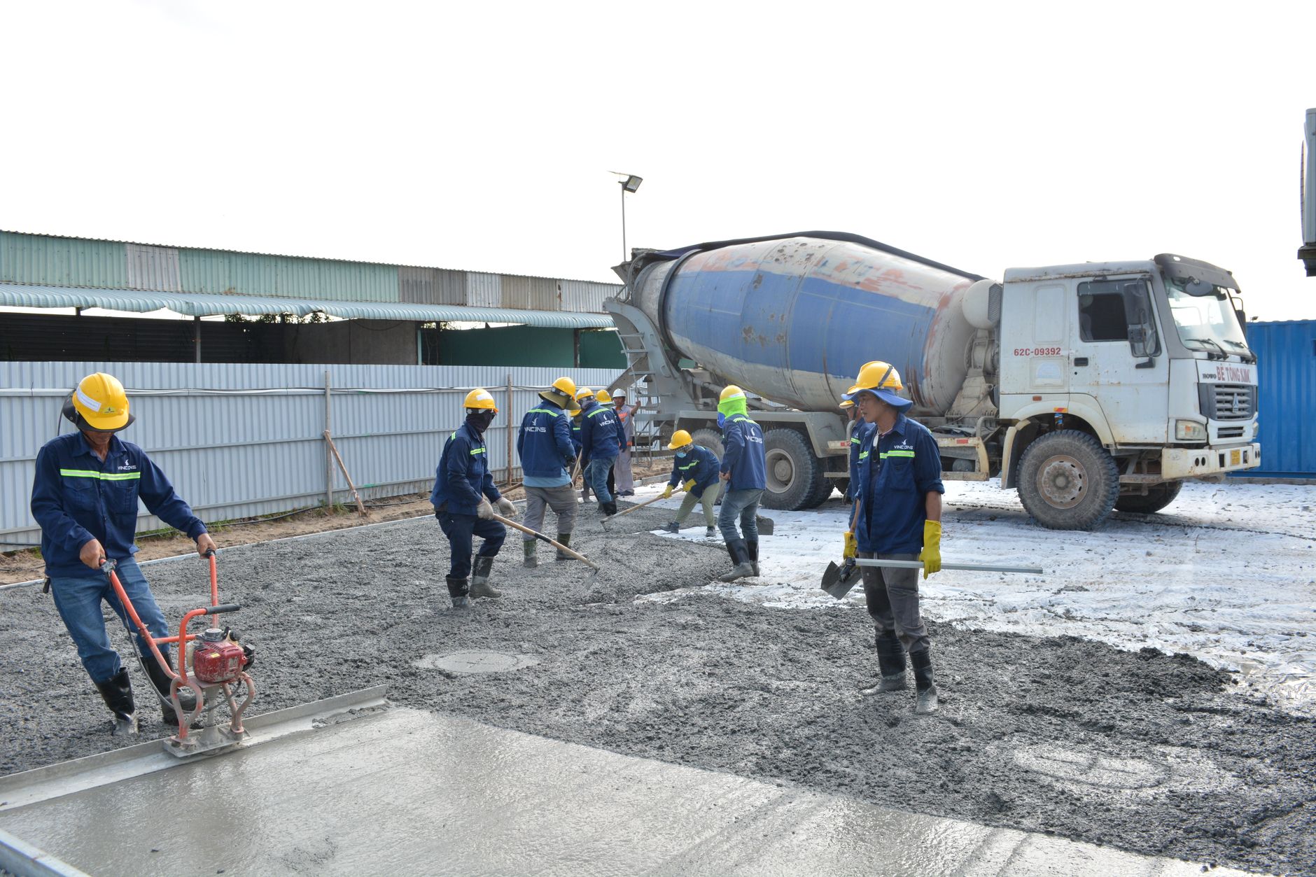 Tradesman pouring concrete mix ratios into a strip foundation trench on a UK building site